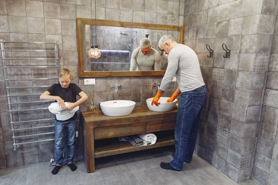 gallery-03 Balai à franges gris appuyé contre un mur texturé, évoquant la simplicité dans un cadre domestique.
